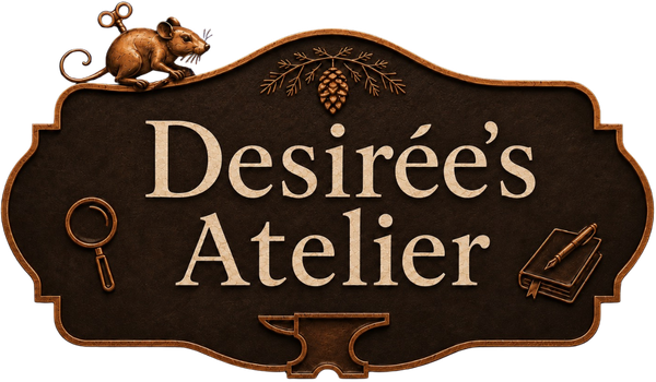 Desirée’s Atelier logo in cream lettering on a dark brown, copper-trimmed workshop sign, decorated with a wind-up mouse, magnifying glass, sequoia branch and cone, notebook and pen, and a small anvil.